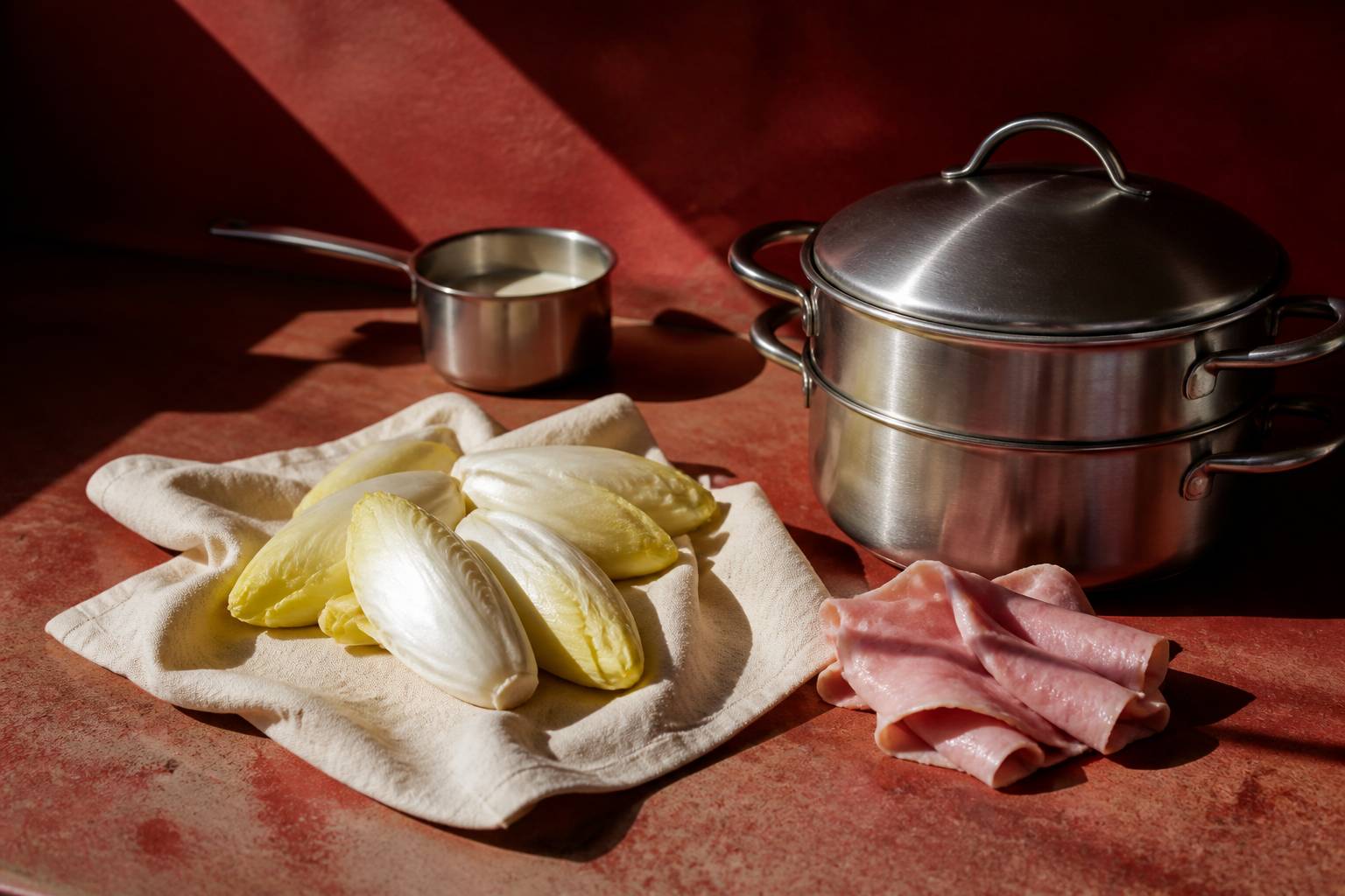 Endives entières près d'un cuit-vapeur avec tranches de jambon pliées