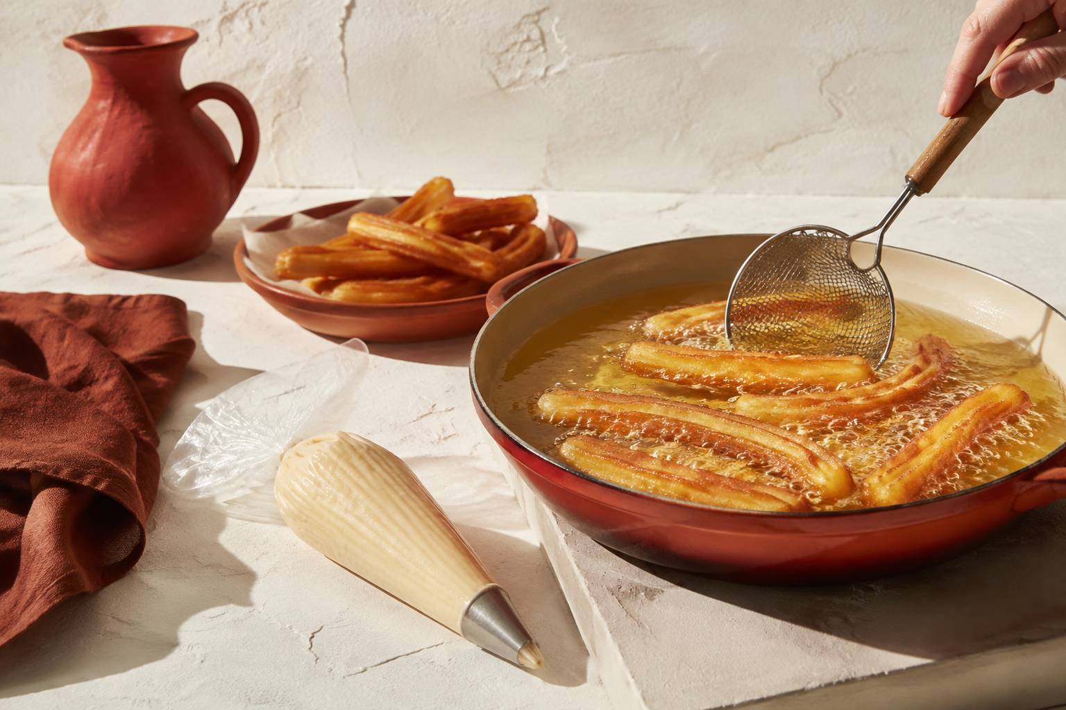 Churros en cours de friture dans l'huile chaude avec une poche à douille