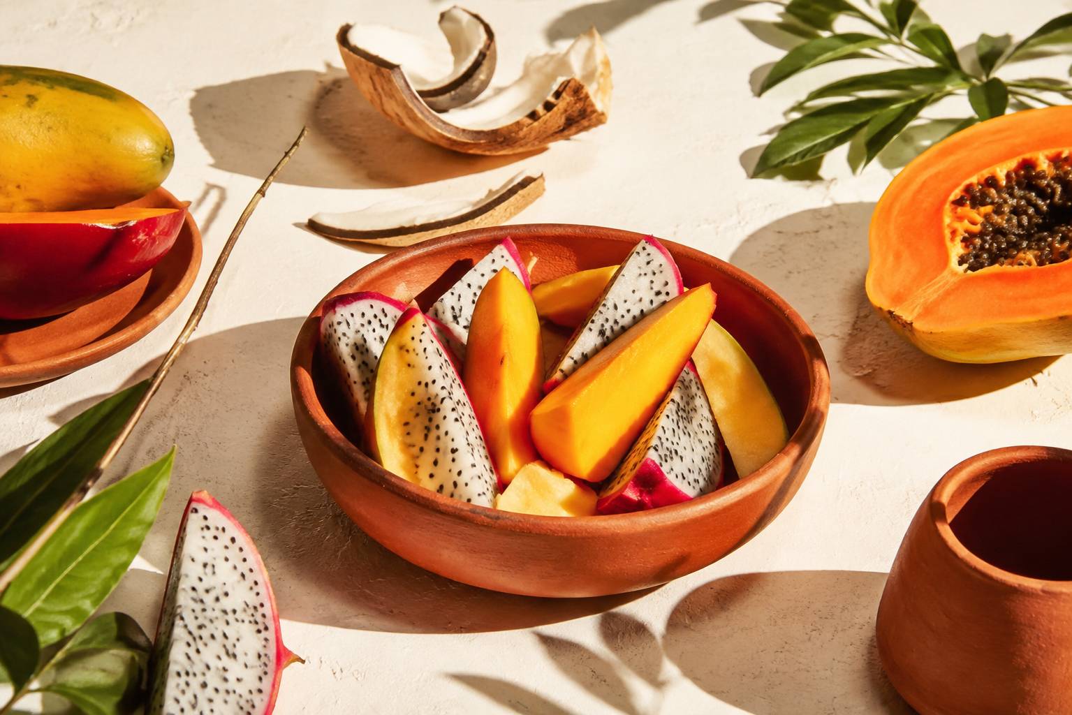 Quartiers de fruits exotiques servis dans une coupelle en terre cuite avec écorces fraîches